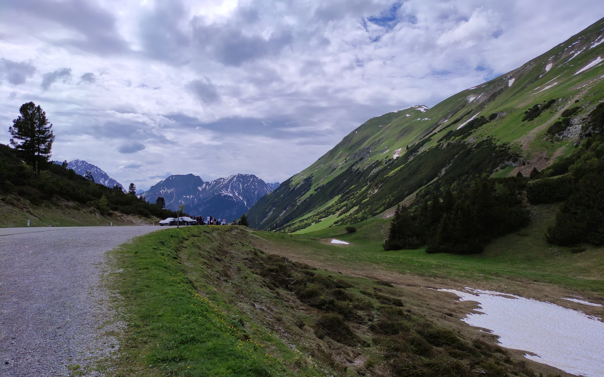 Westblick vom Hahntennjoch über die schmale Passstraße und steile grüne Hänge